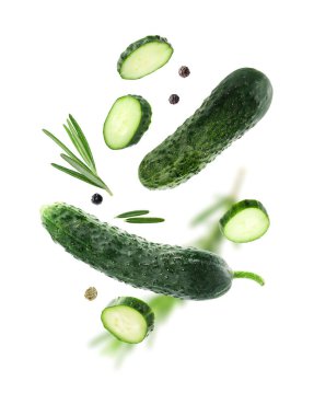 Beyaz arka plana düşen taze salatalıklar, biberiye ve biber taneleri.