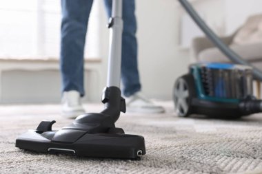 Halıyı elektrikli süpürgeyle temizleyen adam, yakın plan.