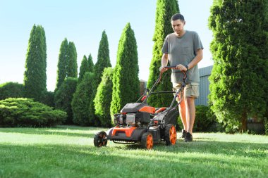 Bahçede çim biçme makinesiyle yeşil çimen biçen adam, metin için alan