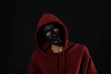 Anonimlik. Karanlık arka planda maskeli bir adam.