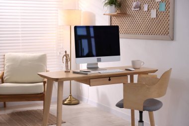 Ev ofisinde ahşap masası, bilgisayarı ve kırtasiyesi olan şık bir iş yeri. İç tasarım