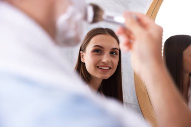 Genç çift aynanın yanında birlikte hazırlanıyor.