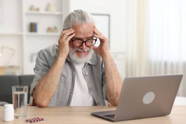 Üst düzey bir adam kapalı bir masada dizüstü bilgisayarla doktorla görüşüyor.