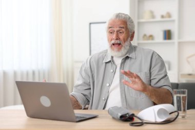 Üst düzey bir adam kapalı bir masada dizüstü bilgisayarla doktorla görüşüyor.