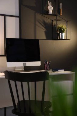 Çalışma masası, bilgisayarı ve kırtasiyesi olan şık bir iş yeri. İç tasarım