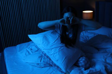 Evde yatağında uykusuzluk çeken, yastıklı hayal kırıklığına uğramış bir kadın.