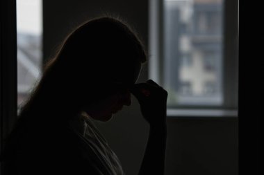 Evdeki üzgün genç kadının silueti, mesaj için yer.