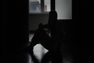 Evdeki üzgün genç kadının silueti.
