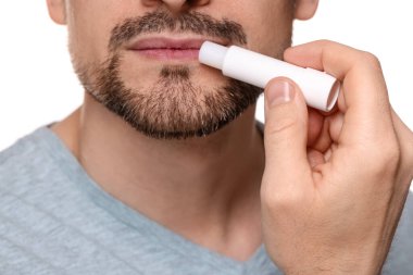 Beyaz arka planda dudaklarına dudak kremi süren adam, yakın plan.