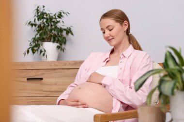 Evdeki koltukta oturan güzel hamile kadın.