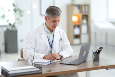 Teletıp. Doktor içeride bilgisayarla hastayla görüntülü konuşma yaparken not alıyor.