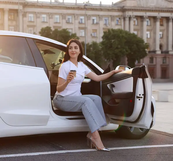 Kahveli kadın modern arabadan dışarı çıkıyor.