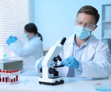 Tıbbi analiz. Laboratuvarda mikroskopla çalışan bilim adamı, seçici odaklanma