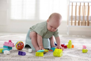 Evdeki lazımlık ve oyuncaklar üzerinde oturan tatlı küçük bebek.