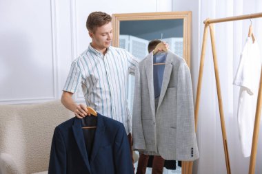 Hazırlanıyor. Genç adam evde kıyafet seçiyor.