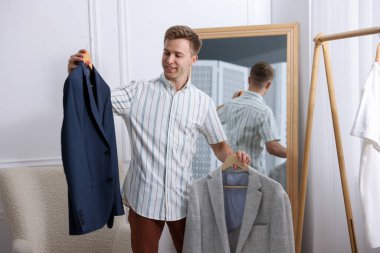 Hazırlanıyor. Genç adam evde kıyafet seçiyor.