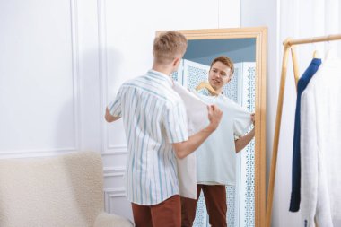 Hazırlanıyor. Genç adam aynanın yanında kıyafet deniyor.