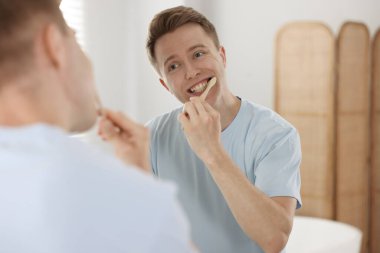 Hazırlanıyor. Evdeki genç adam aynanın yanında dişlerini fırçalıyor.