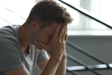 Kapalı alandaki parmaklıkların yanında elleri olan üzgün, yorgun bir adam. Depresyon