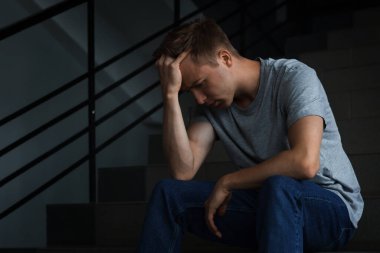 Karanlıkta merdivenlerde oturan üzgün adam. Depresyon