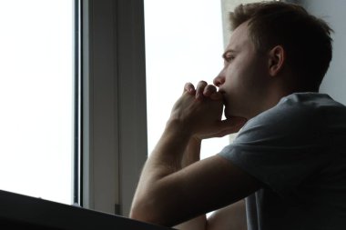 Üzgün, düşünceli, pencereye bakan, düşük açılı, mesaj için yeri olan bir adam. Depresyon