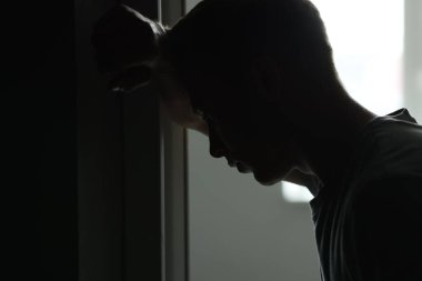 Üzüntü ve depresyon. Karanlıktaki adamın silueti gün ışığına karşı