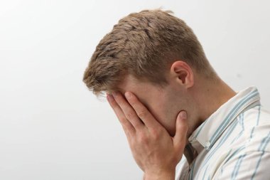 Üzgün, yorgun bir adam, arka planda elleri açık, yüzünü kapatıyor. Metin için boşluk