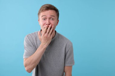 Açık mavi arka planda gülen yakışıklı bir adam. Pozitif duygu