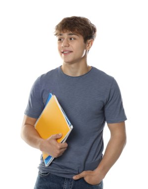 Beyaz arka planda defterleri olan tatlı bir genç çocuk.