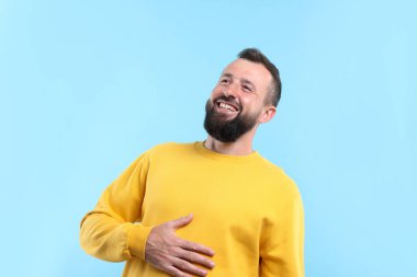 Yakışıklı adam açık mavi arka planda gülüyor.