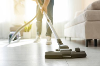 Evin zeminini elektrikli süpürgeyle temizleyen adam, yakın çekim.
