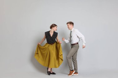Açık gri arka planda dans eden retro kıyafetli mutlu bir çift.