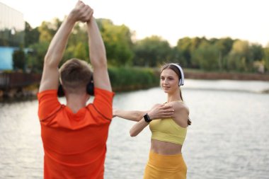 Kulaklıklı bir çift nehir kenarında sabah egzersizi yapıyor.