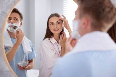 Genç çift aynanın yanında birlikte hazırlanıyor.