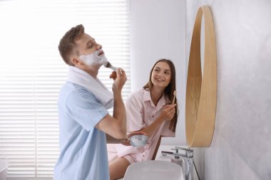 Genç çift aynanın yanında birlikte hazırlanıyor.