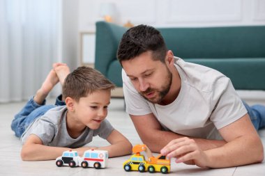 Baba ve oğlu evdeki sıcak zeminde oyuncaklarla oynuyorlar. Isıtma sistemi