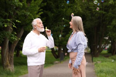 Güzel yaşlı çift parkta sabun köpüğüyle eğleniyor.