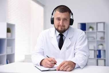 Kulaklıklı doktor içeride online danışmanlık yapıyor.
