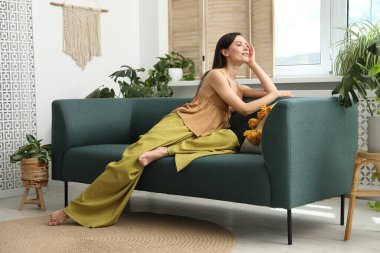 Uyum. Gülümseyen kadın evdeki kanepede dinleniyor.