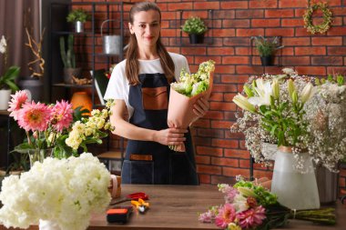 Profesyonel çiçekçi dükkandaki ahşap masada çiçek buketi yapıyor.
