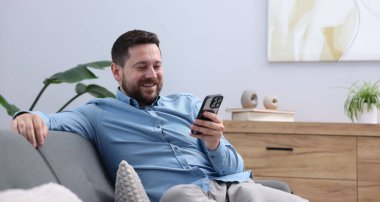 Adam evde akıllı telefondan bir şey izlerken gülüyor, mesaj için yer var.