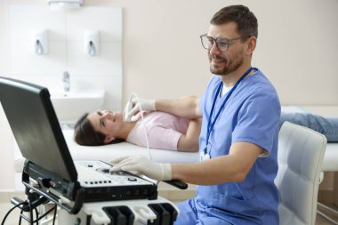 Klinikte kadının tiroid bezini ultrason taraması yapan sonograf.