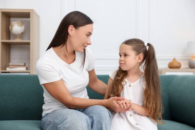 Anne, üzgün kızını evdeki kanepede destekliyor.