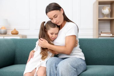 Anne evde üzgün kızını destekliyor ve ona sarılıyor.