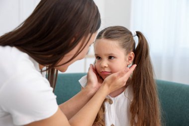Anne, üzgün kızını evdeki kanepede destekliyor.