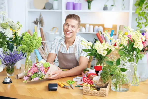 Profesyonel çiçekçi dükkandaki ahşap masada çiçek buketi yapıyor.