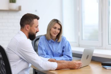 Ofiste dizüstü bilgisayarla çalışan gülümseyen iş ortakları