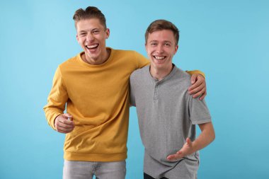 Açık mavi arka planda gülen yakışıklı adamlar. Pozitif duygu