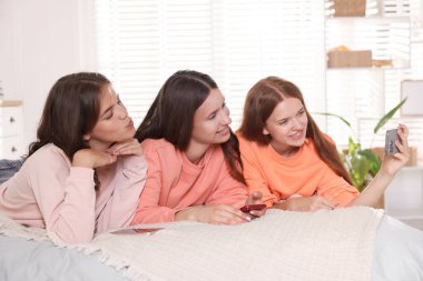 Mutlu arkadaşlar evde yatakta selfie çekiyorlar.