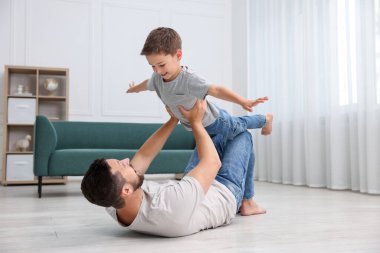 Baba ve oğlu evdeki sıcak zeminde birlikte vakit geçiriyorlar. Isıtma sistemi